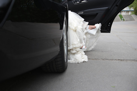 legs of the bride and a white dress when leaving the car with an open doorの写真素材