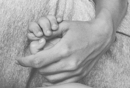 mother gently holds on the belly of her child's small handの写真素材