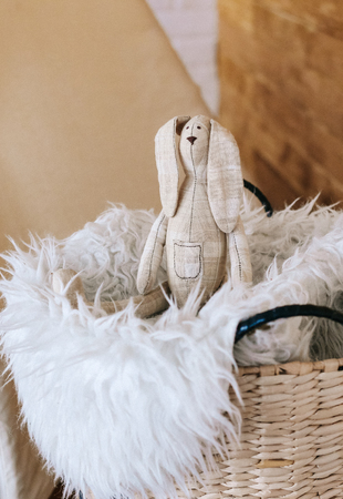 bunny soft handmade toy in the interior of the room basket with fur whiteの写真素材