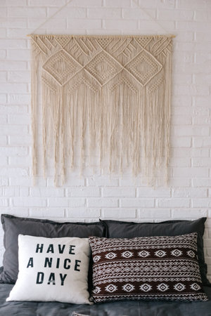 interior of bedroom with bed in boho style decor macrame