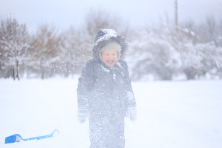 child in a warm jacket actively plays with snow and rejoicesの写真素材