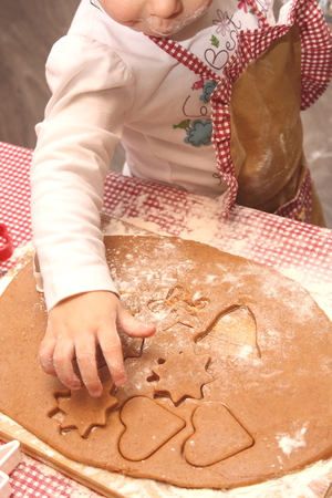 children in an apron are cooking gingerbread cookies in the kitchenの写真素材