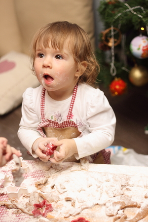 children in an apron are cooking gingerbread cookies in the kitchenの写真素材