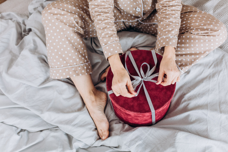 girl in a beige nightgown pajamas opens gifts boxes with ribbons for the new yearの写真素材