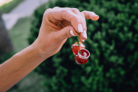 wedding rings on a double cherry in a woman's handの写真素材