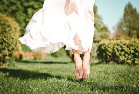 girl outside in a dress and barefoot jumped on the grassの写真素材