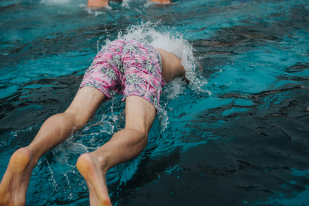 man dives into the pool with splashes of waterの写真素材