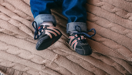 baby on the bed in stylish clothes sneakers and jeans conceptualの写真素材