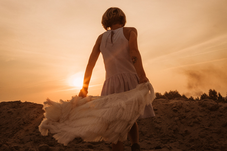 woman on top of the mountain rejoices and dances at sunsetの写真素材