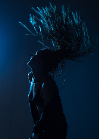 woman with afro pigtails in a raincoat on the dance floor with blue and red lightsの写真素材