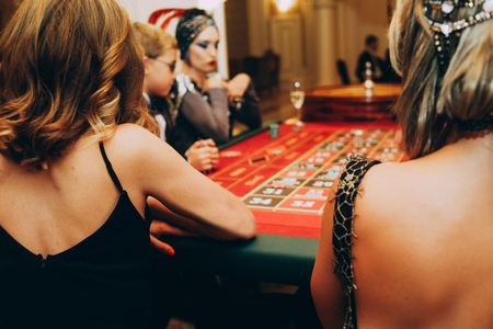 girls in evening dresses and hairstyles from the back at the casino tableの写真素材