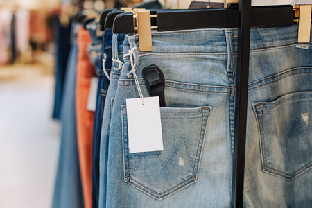 stylish jeans pants in a clothing store on the stands showcase with labels for the inscriptionの写真素材