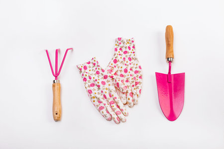 female set decorative hand tools for working in the garden ground with pink gloves and flowersの写真素材