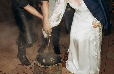 blacksmith and bride in a dress make the product horseshoe red-hot iron on the anvil with a hammer in his handsの写真素材