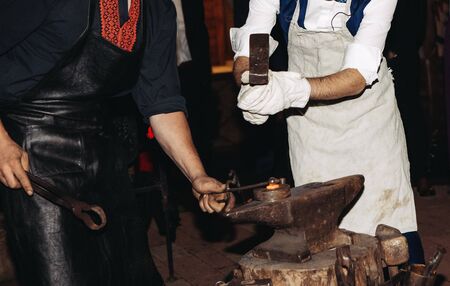 two blacksmith make the product horseshoe red-hot iron on the anvil with a hammer in his handsの写真素材