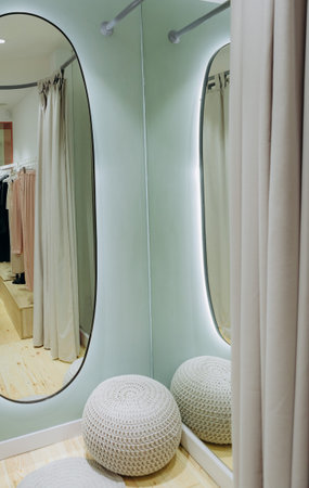 fitting room with mirrors and beige curtains in a clothing store