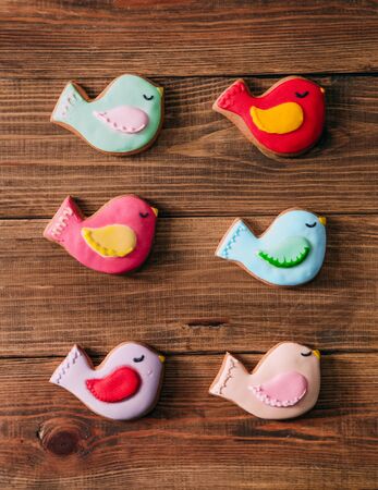 colored drawn birds for cookies with icing on a wooden backgroundの写真素材