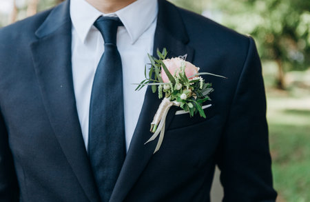 bridegroom in a suit with a tie with a butanier flower in his jacket pocket