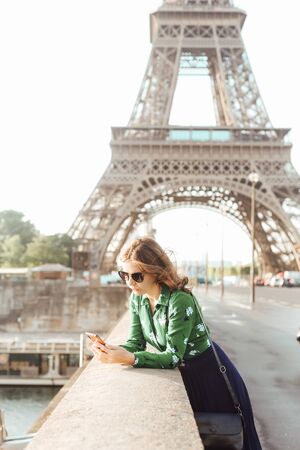 french manicure woman with smartphone against the background of the eiffel tower and reflection in glassesの写真素材