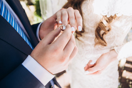 concept tradition putting a wedding ring on the finger of the newlyweds hand close up