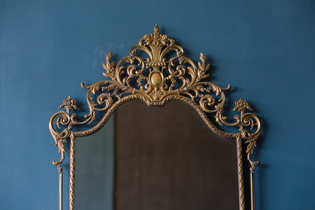 antique mirror in a gold patterned frame on a blue background
