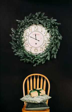 merry christmas arrow on a wall clock with a round conifer wreath and gifts on a chair