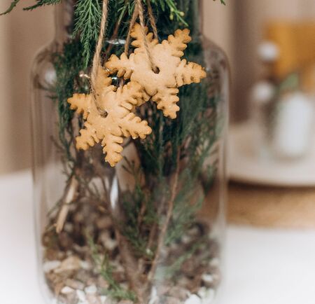 two snowflakes ginger christmas cookies on pine branches in a vase on the tableの写真素材