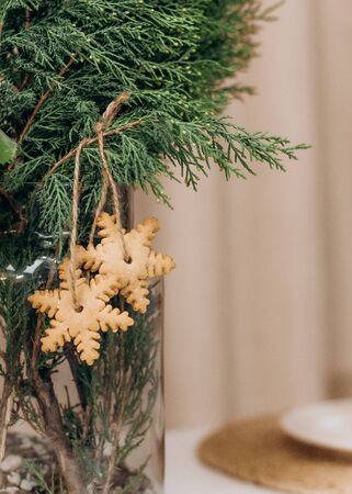 two snowflakes ginger christmas cookies on pine branches in a vase on the tableの写真素材