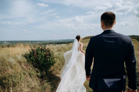 couple in love wedding together outside field path landscape sky veil wind freedomの写真素材