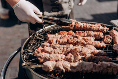 chef prepares meat on a charcoal grill outside at a partyの写真素材