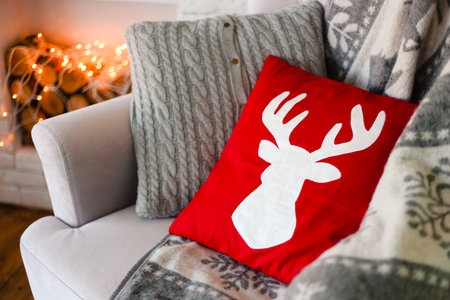 red pillow with christmas reindeer symbol on the armchair by the fireplace