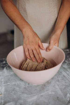 female hands kneading dough for homemade bread in a bowlの写真素材