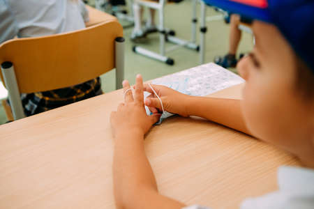 schoolboy at the table with a mask in his hands listens to a lessonの写真素材
