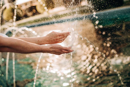 hands of lovers with splashing fountain playing with water summer freshnessの写真素材