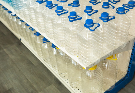 many bottles for water with a lid and a handle standing in a row on the display case