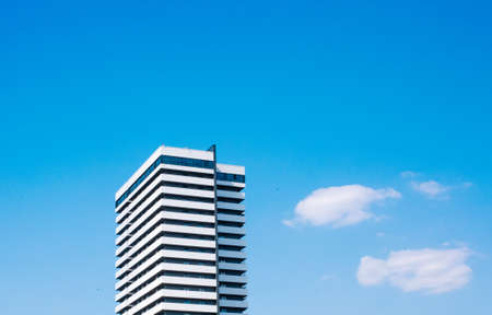 one skyscraper white building rises in the sky with clouds construction conceptの写真素材