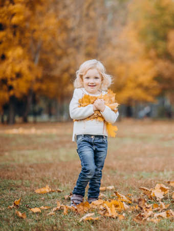happy children play in autumn park throw up fallen leavesの写真素材