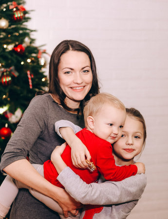 mom with kids girls watching gifts under the christmas tree