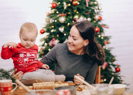 mom and daughters cooking christmas gingerbread in a room with a christmas treeの写真素材