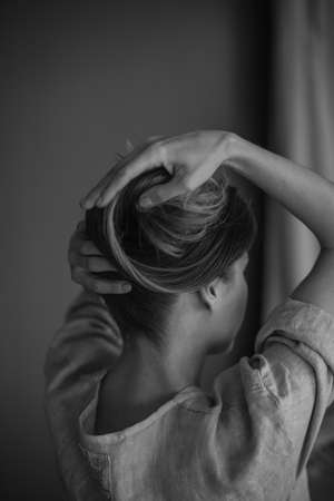 woman backside closeup straightens her hairstyle with her handの写真素材