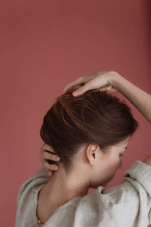 woman backside closeup straightens her hairstyle with her handの写真素材