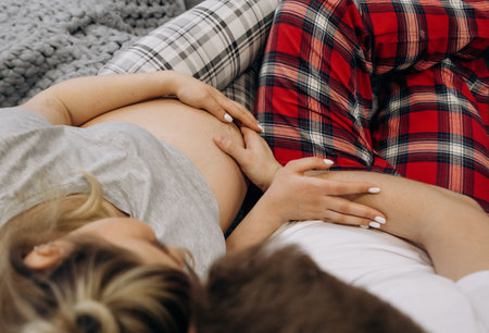 pregnant woman with husband create heart sign on belly family houseの写真素材