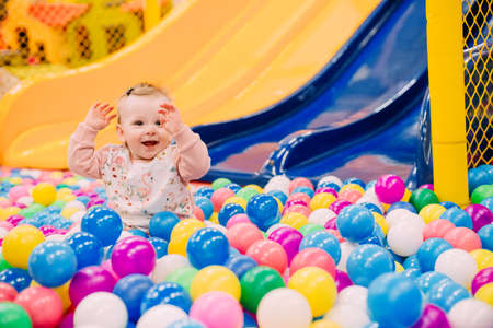 cheerful small child on a playground with a slide and a lot of colorful ballsの写真素材
