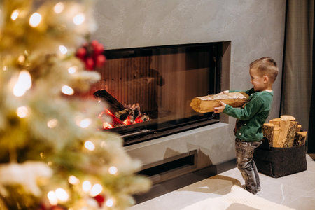 child boy carries firewood to the fireplace christmas eveの写真素材