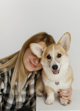 woman with a pet corgi dog plays and teaches furry friend commands inside the house