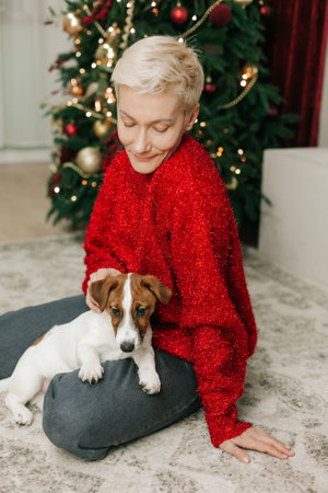 woman with pet puppy jack russell celebrating christmas on tree decoration backgroundの写真素材