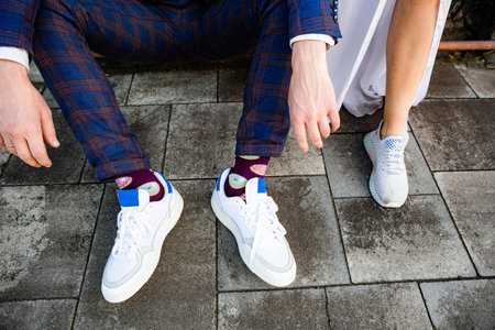 modern wedding bride and groom outside in colored suit and sneakers and socksの写真素材