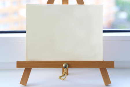 Sheet on the windowsill. A small wooden easel and an empty sheetの写真素材