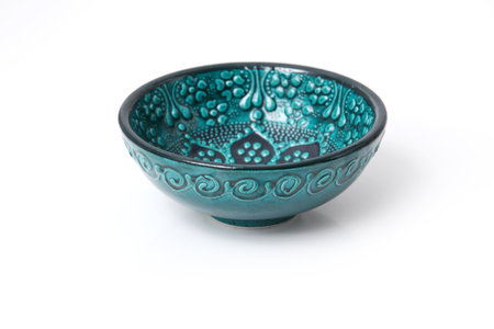 Green bowl with wave ornament on white background. Dark glaze on ceramics. Rustic ornament with flowers.の写真素材