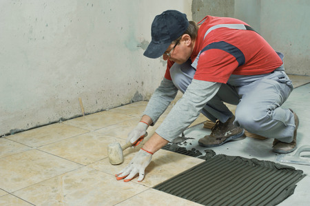 Laying Ceramic Tiles. Tiler knocking on the tiles with a rubber malletの写真素材